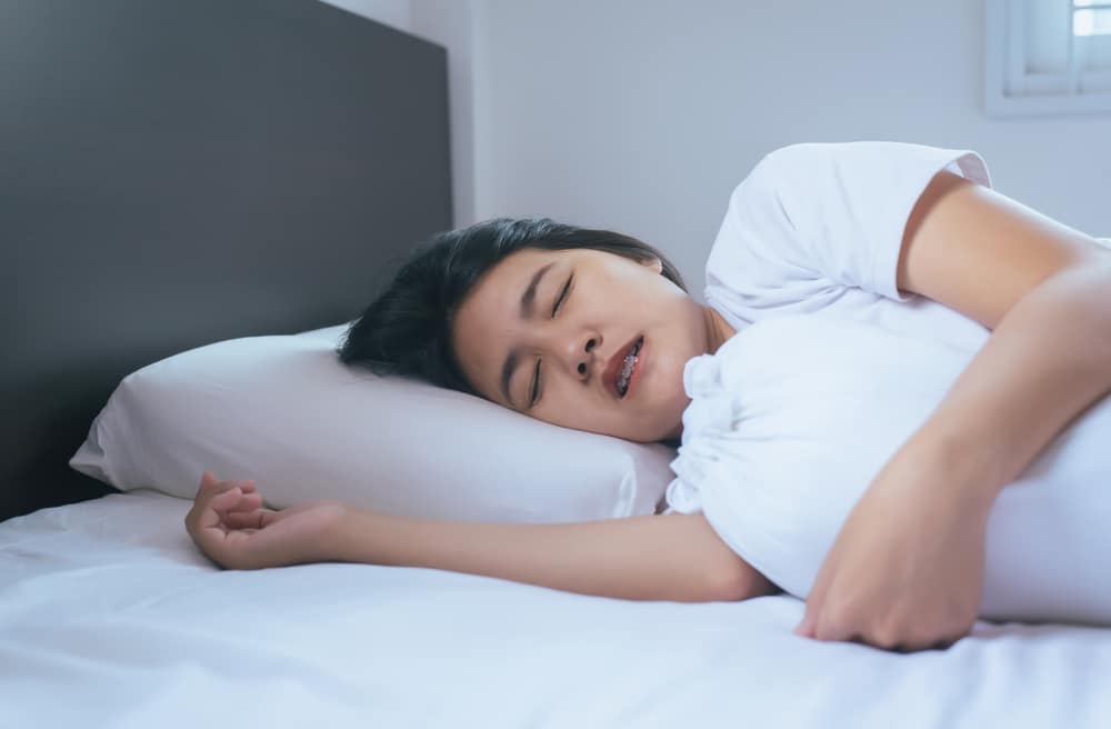 Woman grinding her teeth while sleeping in bed